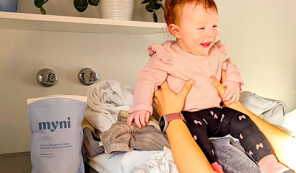 mom taking care of washing her baby's clothes in the machine with myni's delicate baby laundry detergent tablets