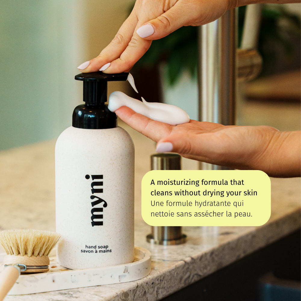 Hand applying myni hand soap to a hand with a blurred background