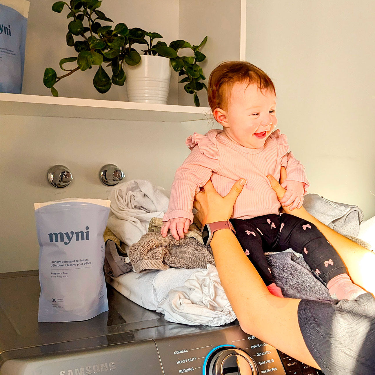 myni baby laundry detergent with mom and baby on the washing machine lifestyle